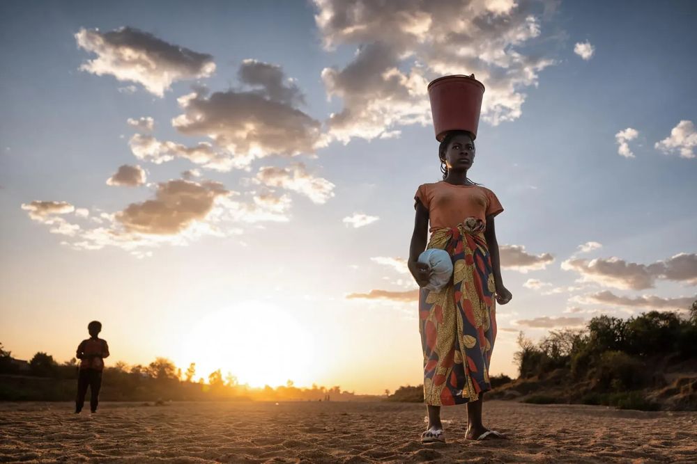 A girl in a dessert region carrying water 