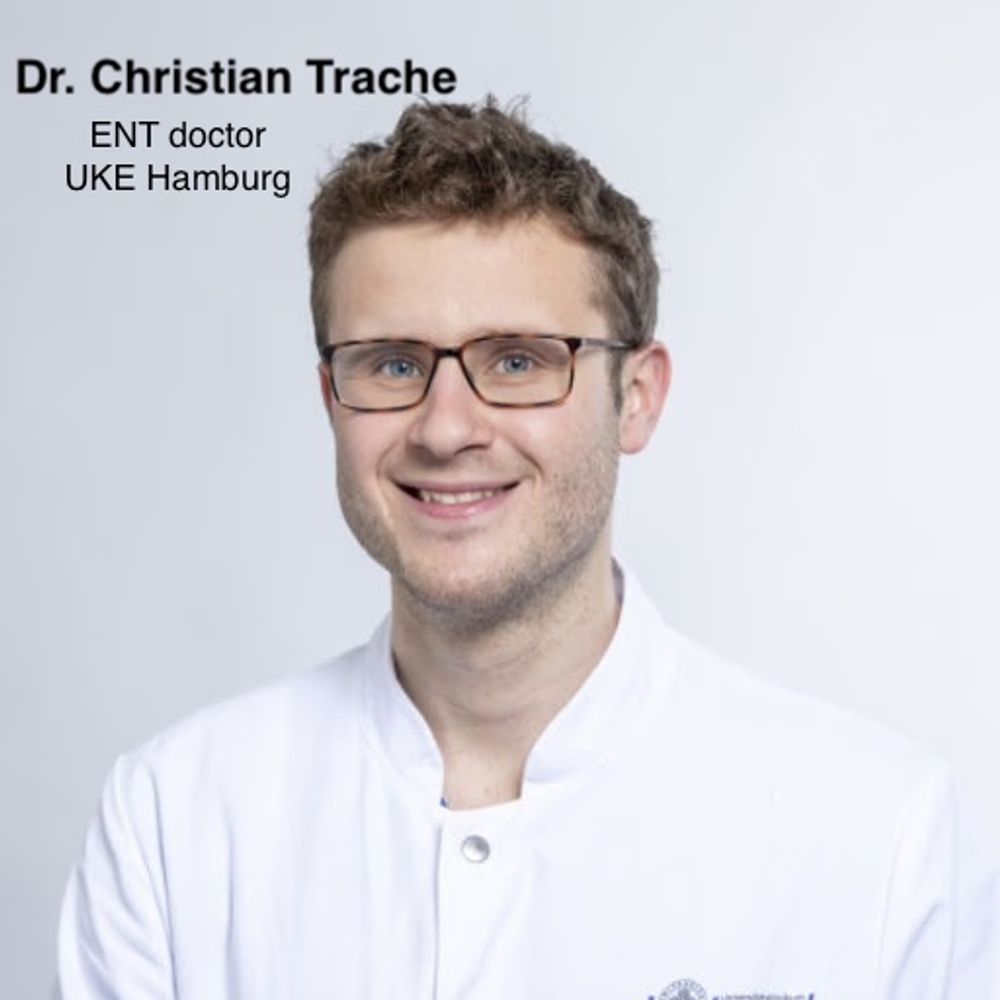 Porträtfoto von Dr. Christian Trache, HNO-Arzt am UKE Hamburg. Er trägt einen weißen Arztkittel und eine Brille und lächelt in die Kamera. Der Hintergrund ist hellgrau. Text auf dem Bild: „Dr. Christian Trache – ENT doctor, UKE Hamburg“.